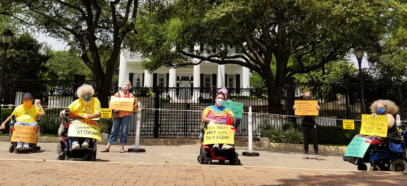 ADAPT and PACT members in wheelchairs and on foot wearing PPE holding protest signs in front of Texas Governor's Mansion
