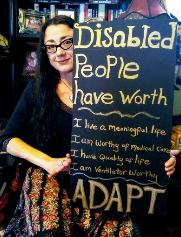Lydia from Gulf Coast ADAPT in her wheelchair in a colorful skirt and glasses holding a sign that says Disabled People Have Worth. I have a meaningful life. I am worthy of medical care. I have quality of life. I am ventilator worthy. ADAPT.
